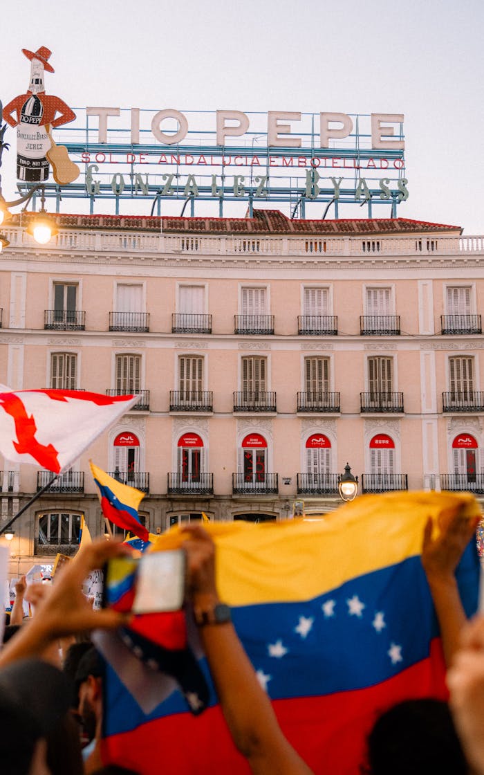 Crowd waving flags in front of Tio Pepe sign in Madrid's Plaza del Sol.