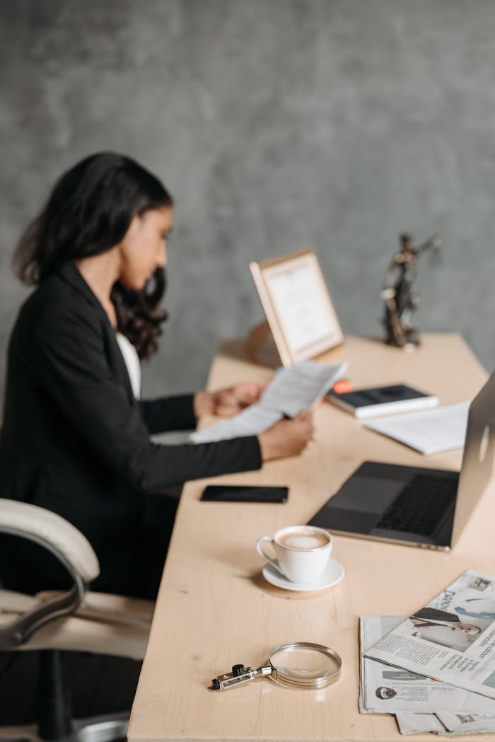 services-02 Asian woman in office attentively reading paperwork at a desk.